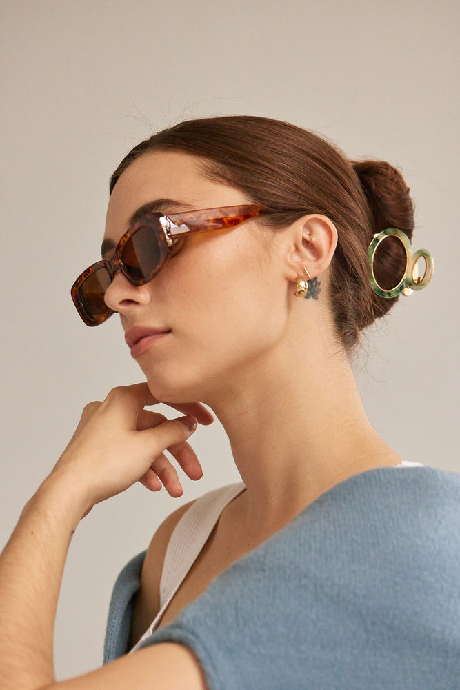 Sophisticated style outfit features a cardigan over a white tank, and a green marble, round hair clip and tortoise shell sunglasses.