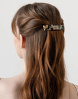 France Luxe medium French barrette for women pictured holding straight, brown hair in a half up hairstyle.