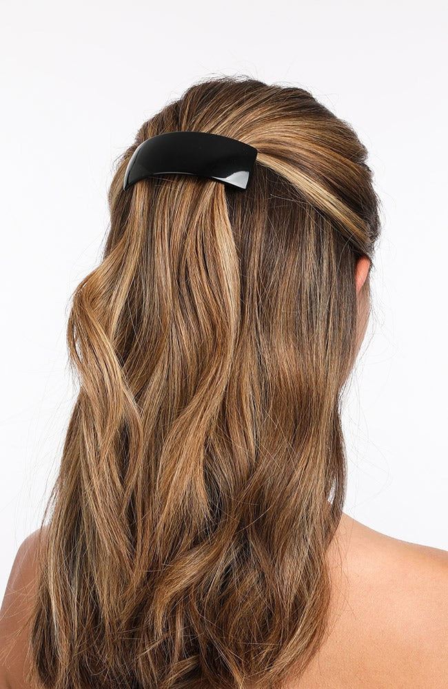 France Luxe large, black barrette for women pictured holding wavy, blonde hair in a half up hairstyle.