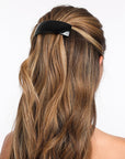 France Luxe large, black barrette for women pictured holding wavy, blonde hair in a half up hairstyle.