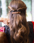 France Luxe medium, brown barrette for women pictured holding straight, brown hair in a half up hairstyle.