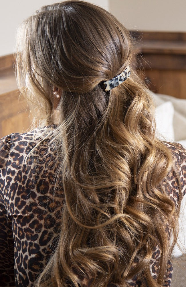France Luxe medium, ivory tortoiseshell barrette for women pictured holding wavy, brown hair in a half up hairstyle.