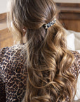 France Luxe medium, ivory tortoiseshell barrette for women pictured holding wavy, brown hair in a half up hairstyle.