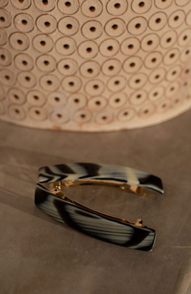 Two Classic French Barrettes in a horn inspired black &amp; cream pattern, pictured next to a basket.