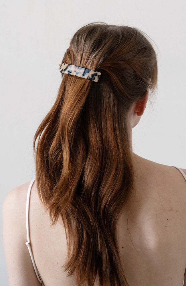 France Luxe medium French barrette for women pictured holding straight, brown hair in a half up hairstyle.