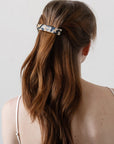 France Luxe medium French barrette for women pictured holding straight, brown hair in a half up hairstyle.