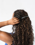 France Luxe long, light blue barrette for women pictured holding curly, brown hair in a half up hairstyle.