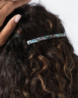 France Luxe long French barrette for women pictured holding curly, brown hair in a half up hairstyle.
