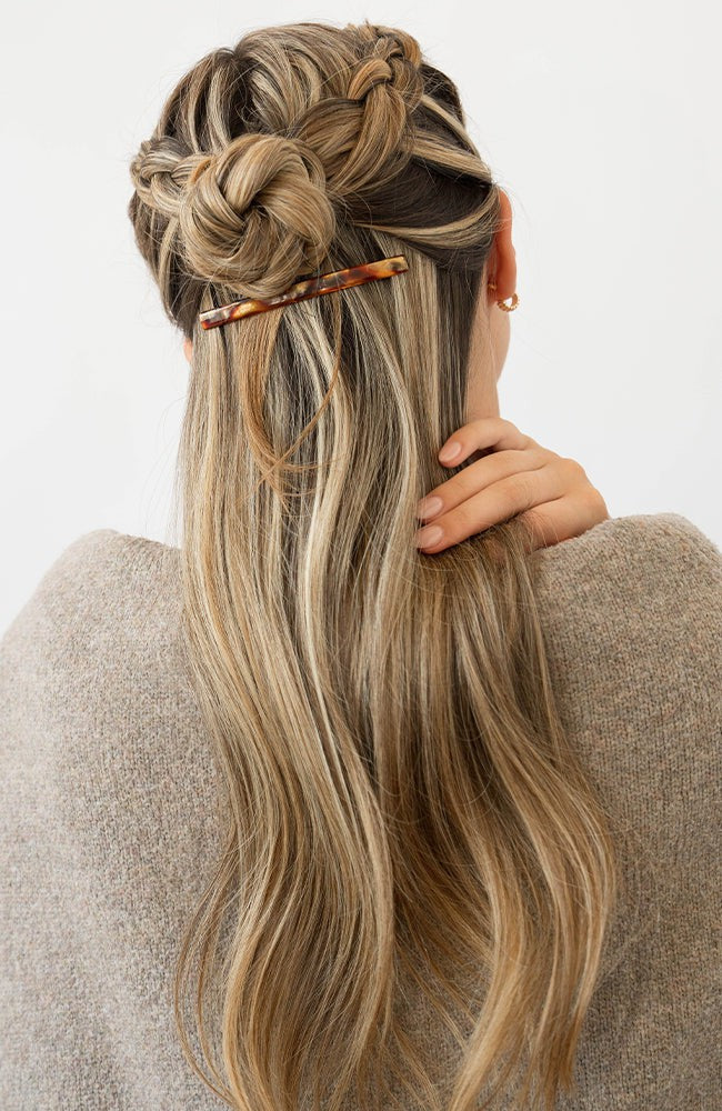 France Luxe long, brown barrette for women pictured holding straight, blonde hair in a half up hairstyle.