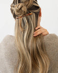 France Luxe long, brown barrette for women pictured holding straight, blonde hair in a half up hairstyle.
