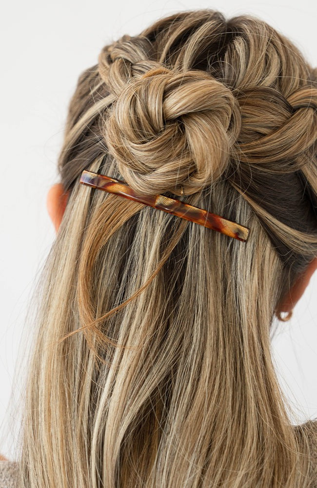 France Luxe long French barrette for women pictured holding straight, blonde hair in a half up bun hairstyle.
