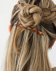 France Luxe long French barrette for women pictured holding straight, blonde hair in a half up bun hairstyle.