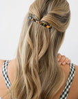 France Luxe long, classic tortoiseshell barrette for women pictured holding wavy, blonde hair in a half up hairstyle.
