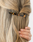 France Luxe long French barrette for women pictured holding straight, blonde hair in a half up hairstyle.