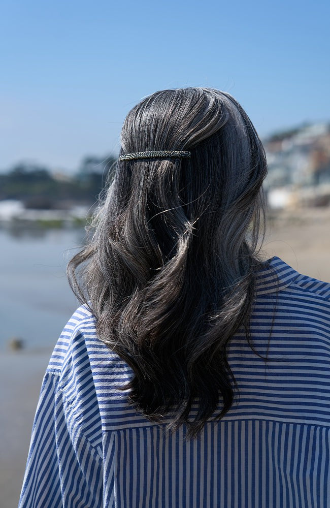 France Luxe long French barrette for women pictured holding straight, gray hair in a half up hairstyle.