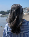 France Luxe long French barrette for women pictured holding straight, gray hair in a half up hairstyle.