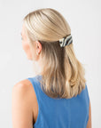 France Luxe large French barrette for women pictured holding straight, blonde hair in a half up hairstyle.