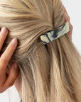 France Luxe medium, black & white barrette for women pictured holding straight, blonde hair in a half up hairstyle.