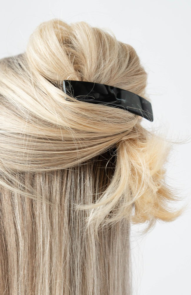 France Luxe medium French barrette for women pictured holding straight, blonde hair in a half up hairstyle.