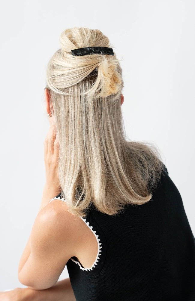 France Luxe medium French barrette for women pictured holding straight, blonde hair in a half up hairstyle.