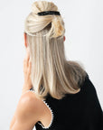 France Luxe medium French barrette for women pictured holding straight, blonde hair in a half up hairstyle.