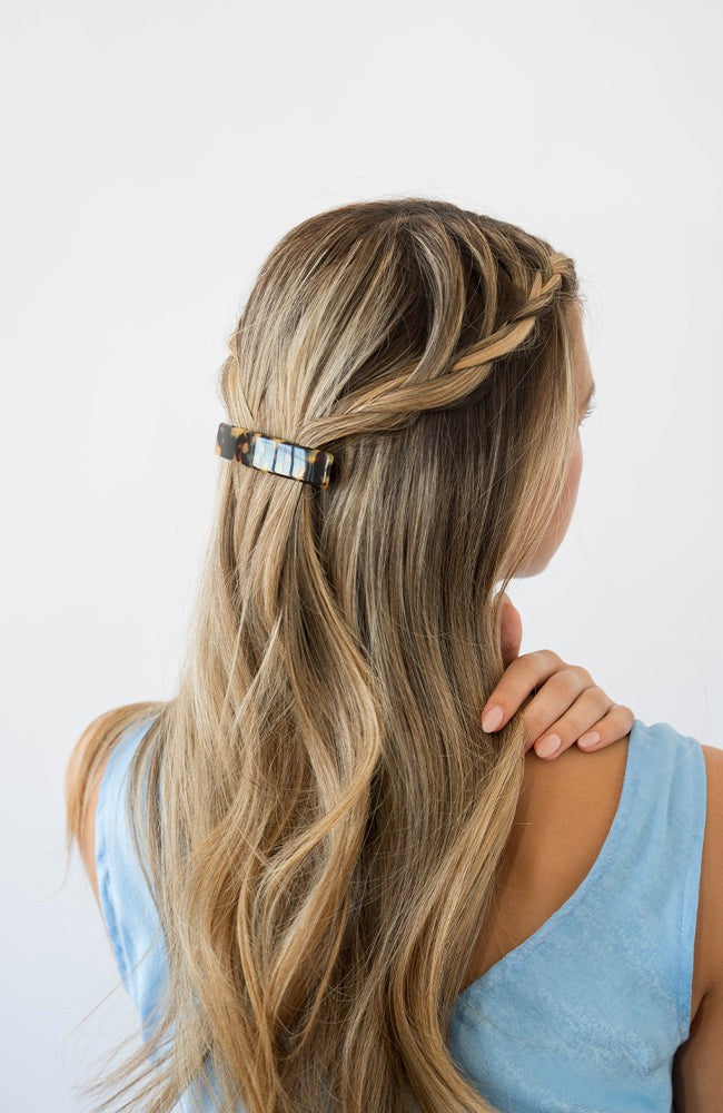 France Luxe medium French barrette for women pictured holding straight, blonde hair in a braided hairstyle.