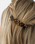 France Luxe medium French barrette for women pictured holding straight, blonde hair in a braided hairstyle.