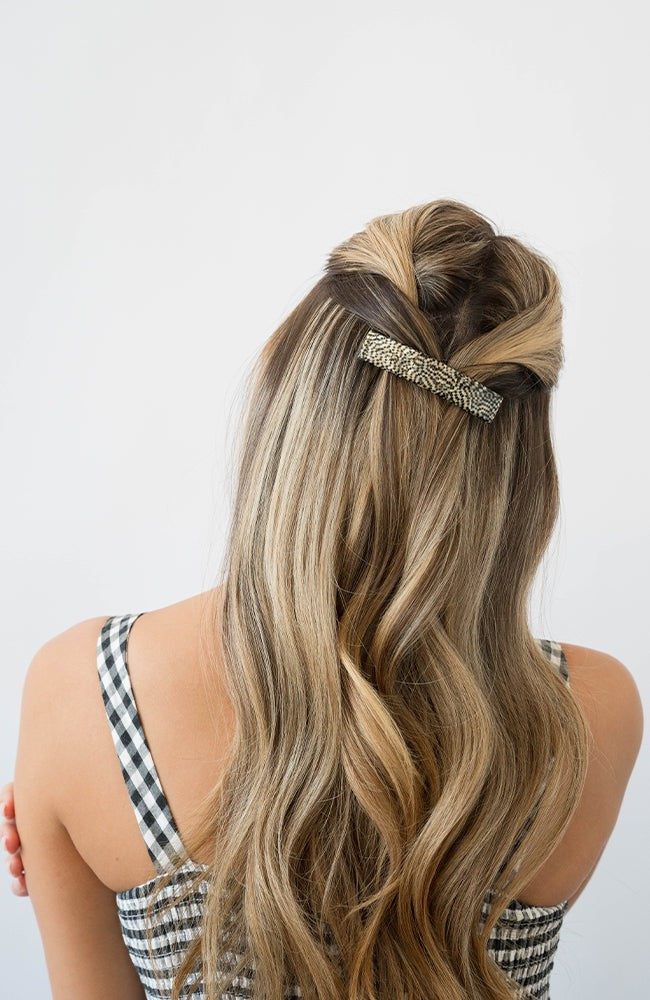 France Luxe medium, silver barrette for women pictured holding wavy, blonde hair in a half up hairstyle.