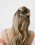 France Luxe medium, silver barrette for women pictured holding wavy, blonde hair in a half up hairstyle.