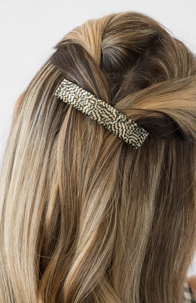 France Luxe medium French barrette for women pictured holding straight, blonde hair in a half up hairstyle.