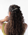 France Luxe medium, ivory tortoiseshell barrette for women pictured holding curly, brown hair in a half up hairstyle.