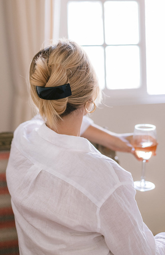 Woman with straight, blonde hair styled in a twist updo with a France Luxe large, Black barrette.