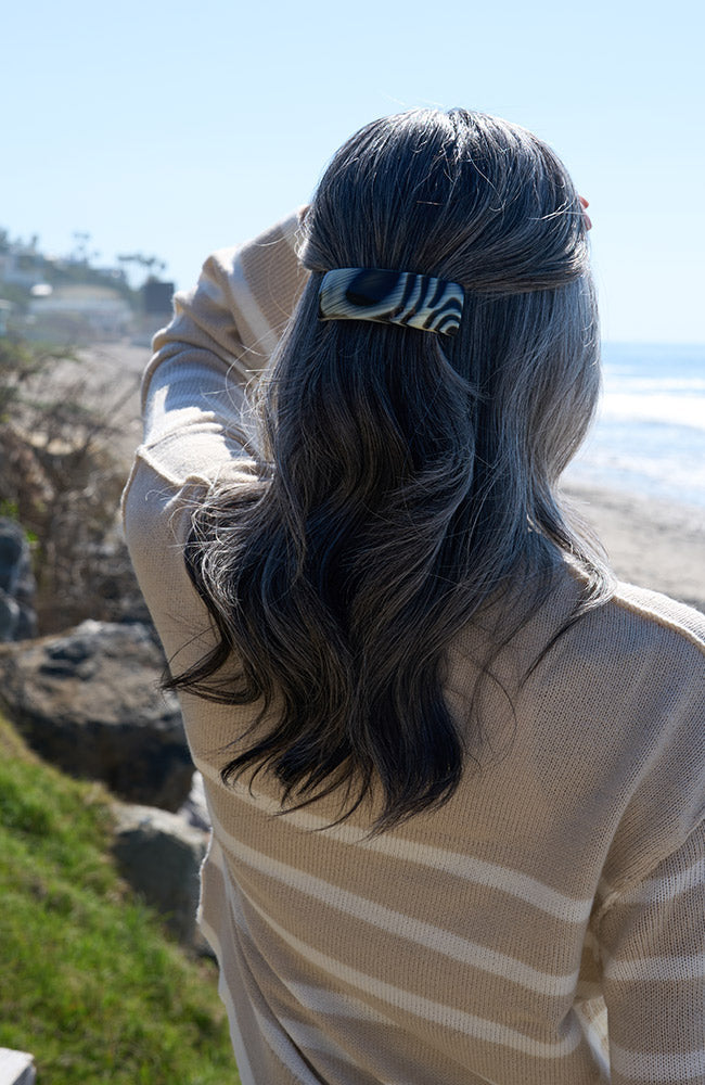 France Luxe large, black &amp; white barrette for women pictured holding straight, gray hair in a half up hairstyle.