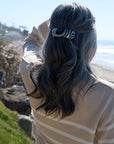 France Luxe large, black & white barrette for women pictured holding straight, gray hair in a half up hairstyle.