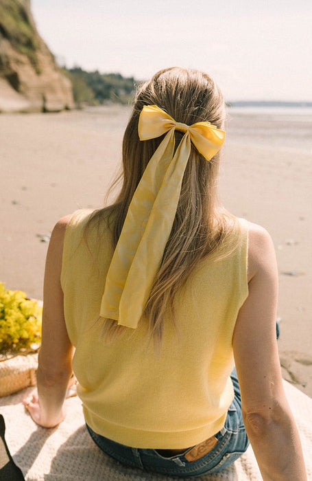 Yellow silk bow hair clip holding back hair at the beach, Long Tail Bow Barrette, Silk Charmeuse Plantain by L. Erickson USA, handmade in America