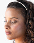France Luxe marbled ivory white headband for women pictured holding curly, brown hair in a loose hairstyle.