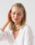 France Luxe thin headband in a golden sand and rich brown color, pictured holding straight, blonde hair in a loose hairstyle.