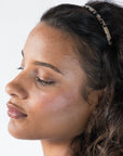 France Luxe thin headband in a Ivory Tortoise Shell color, pictured holding curly, brown hair in a loose hairstyle.