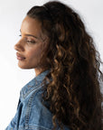 France Luxe thin headband in a metallic burnt sienna and deep chestnut color, pictured holding curly, brown hair in a loose hairstyle.