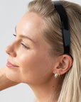 France Luxe classic black headband for women pictured holding straight, blonde hair in a loose hairstyle.