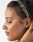 France Luxe wide headband in a marbled gray and charcoal color, pictured holding curly, brown hair in a loose hairstyle.