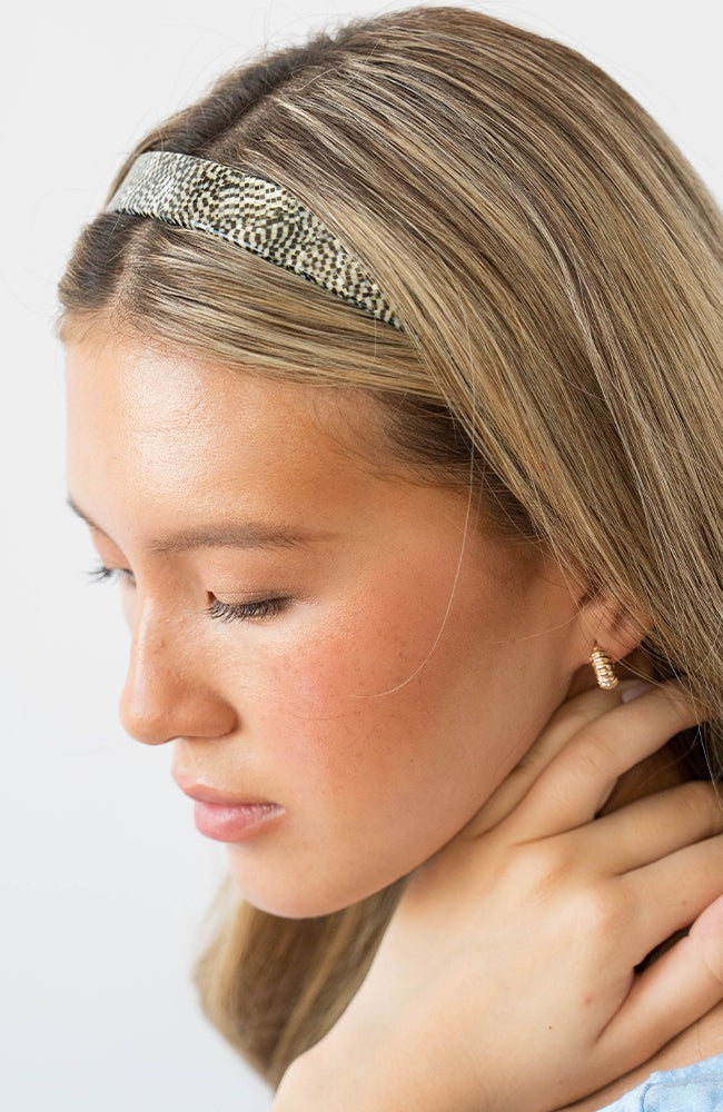 France Luxe pixelated mosaic of silver with black headband for women pictured holding straight, blonde hair in a loose hairstyle.