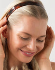 France Luxe rich amber and mahogany brown headband for women pictured holding straight, blonde hair in a loose hairstyle.