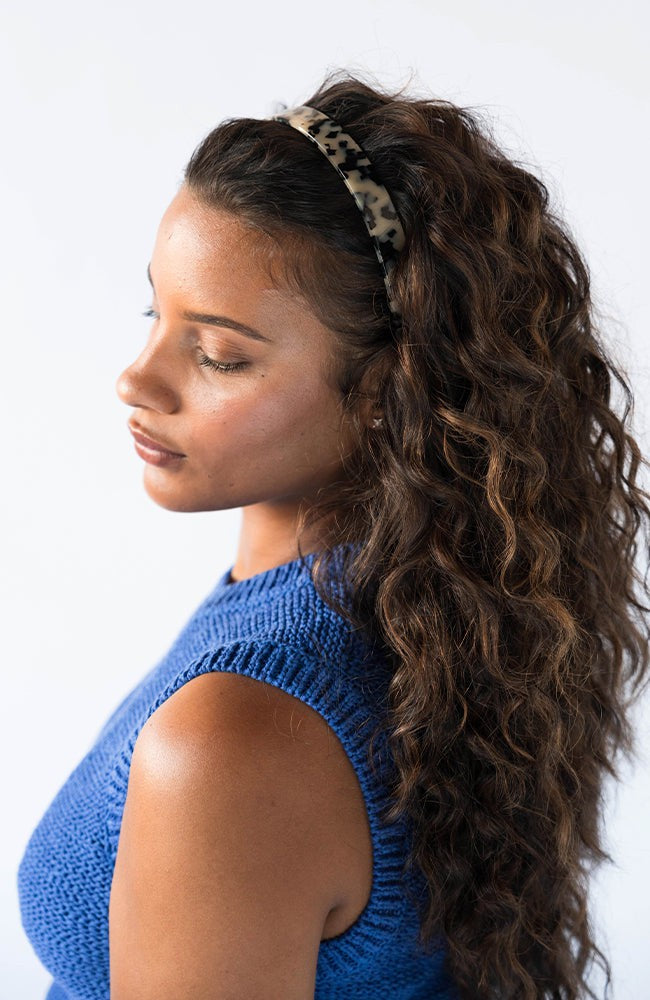 France Luxe Ivory Tortoise Shell headband for women pictured holding curly, brown hair in a loose hairstyle.
