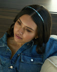 France Luxe thin headband in a light blue, faux shell color, pictured holding straight, brown hair in a loose hairstyle.