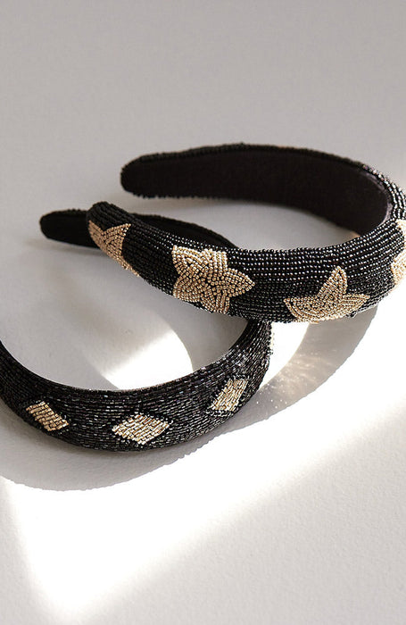 Two beaded black, wide headbands. The top one is padded and features gold stars. The bottom headband features gold diamond shapes.