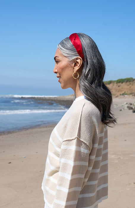 Pleated red silk headband holding back hair on the beach