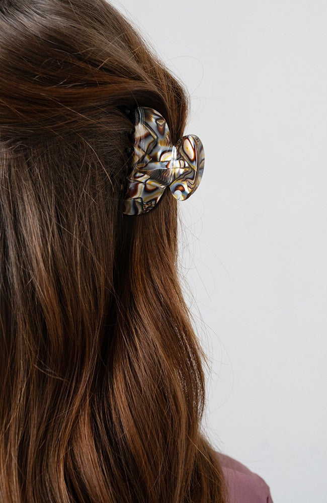 France Luxe small, grey claw hair clip for women pictured holding straight, brown hair in a casual half up hairstyle.