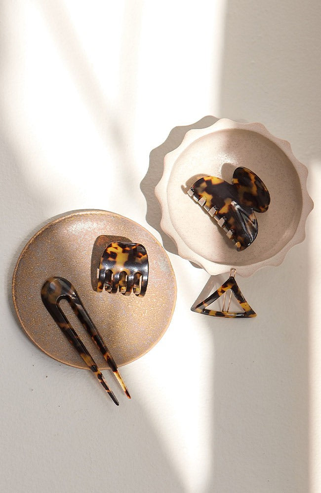 Timeless French hair accessories, Tortoise hair clips, a small triangle barrette, and a two-prong hair pin.