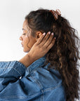 France Luxe small, brown claw hair clip for women pictured holding curly, brown hair in a half up hairstyle.